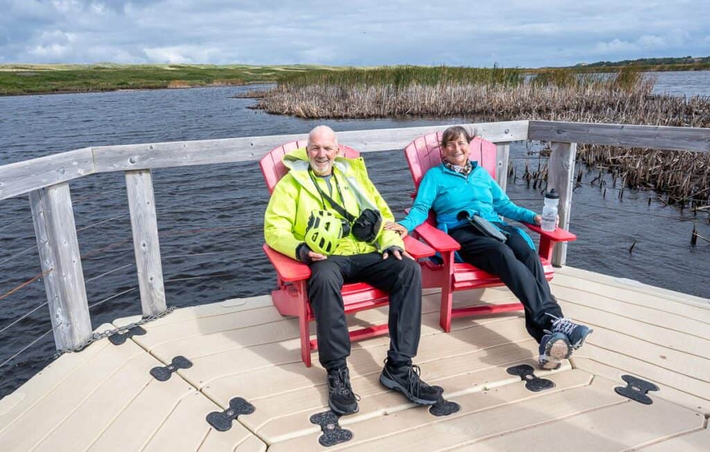 My friends enjoy a Parks Canada red chair moment on the floating boardwalk in Prince Edward Island National Park