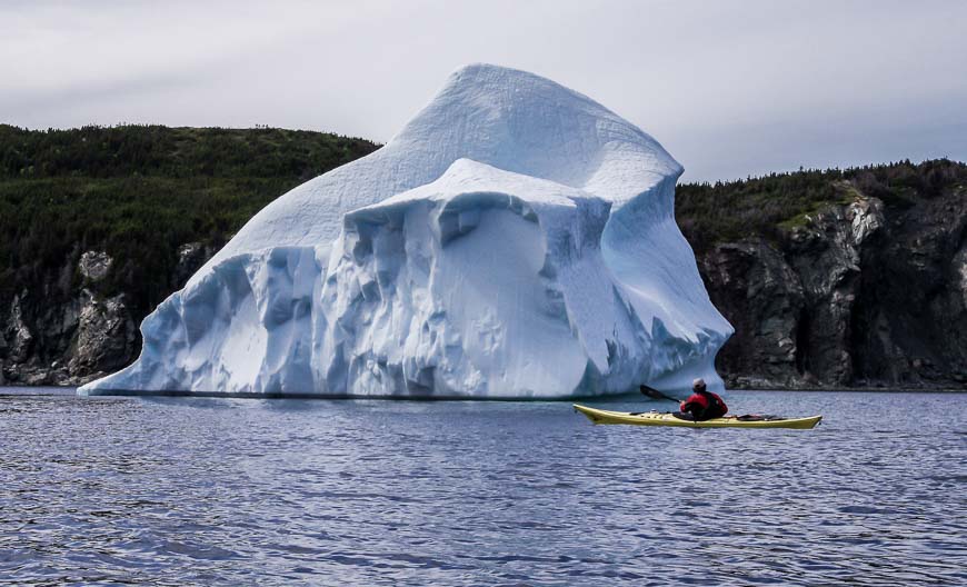 Coastal trail in Newfoundland with iceberg and fishing boat in the