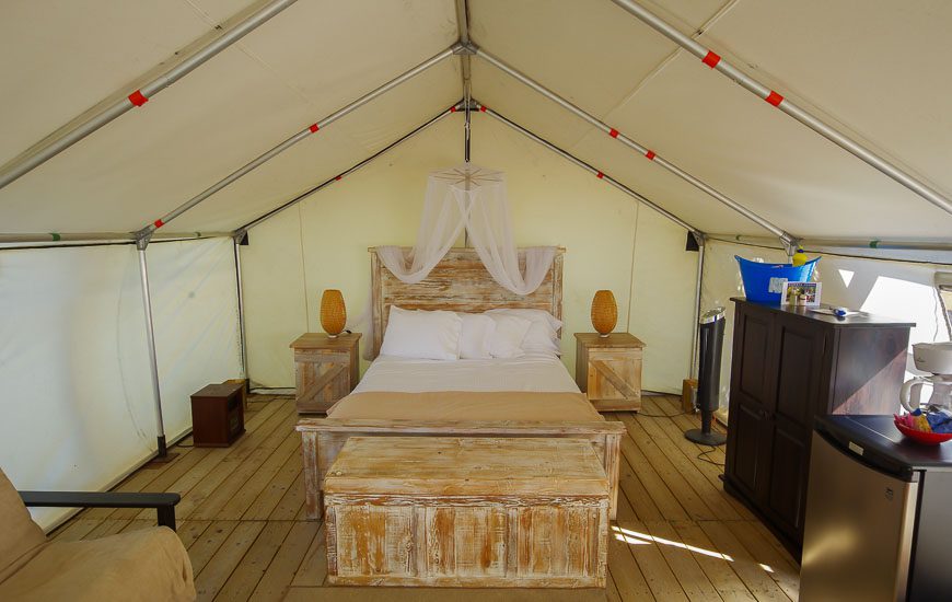 Comfort camping tents come with locally made furniture, a mini fridge, linens, kitchenware