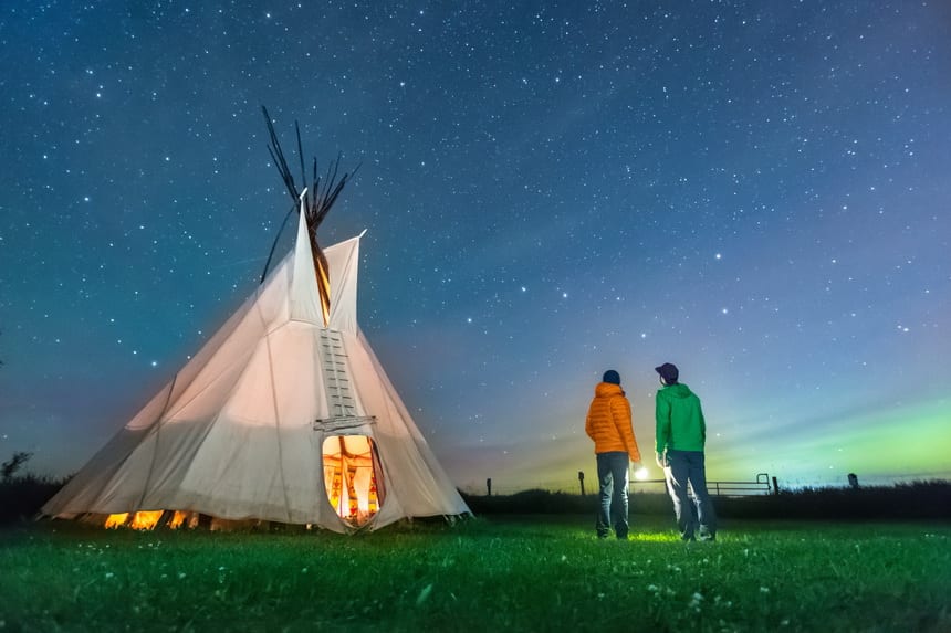 Visitors gazing at the Big Dipper stars outside a Tipi on a starry night in August, at Rocky Mountain House National Historic Site in Alberta 