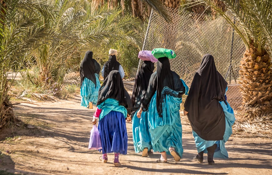 Women fully covered and on their way to a wedding carrying sacks of sugar as a gif