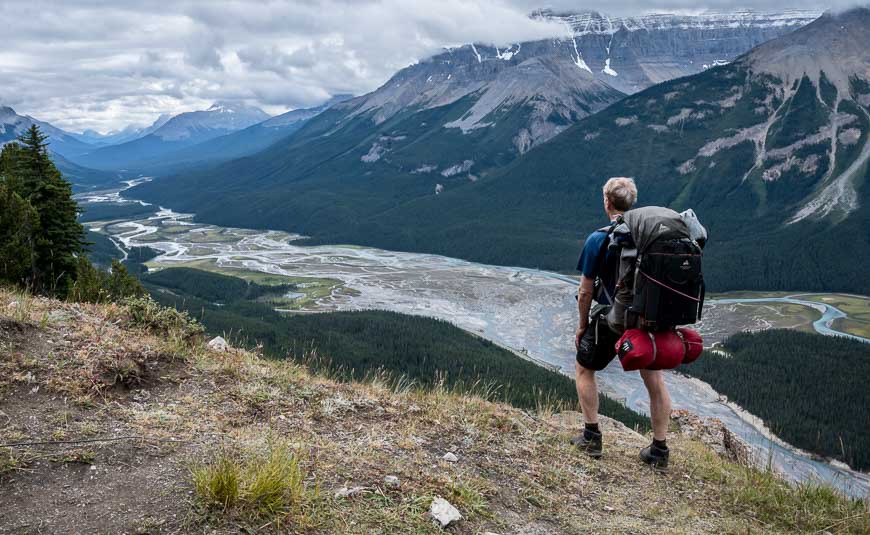 Backpacker man exploring sunset rocky mountains alone hiking