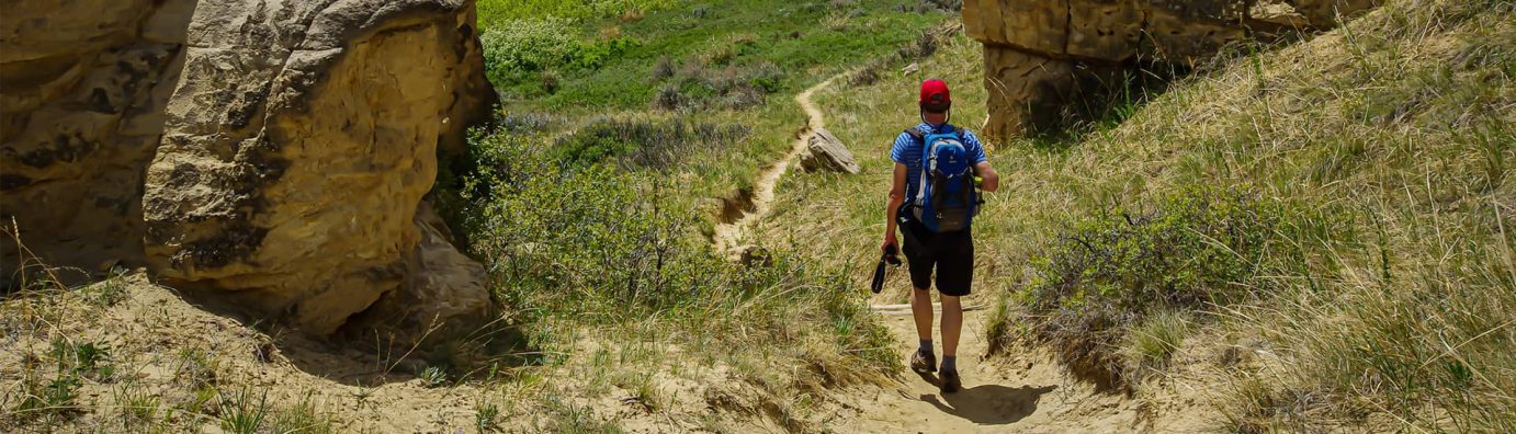Hiker walking down trails with packed backpack