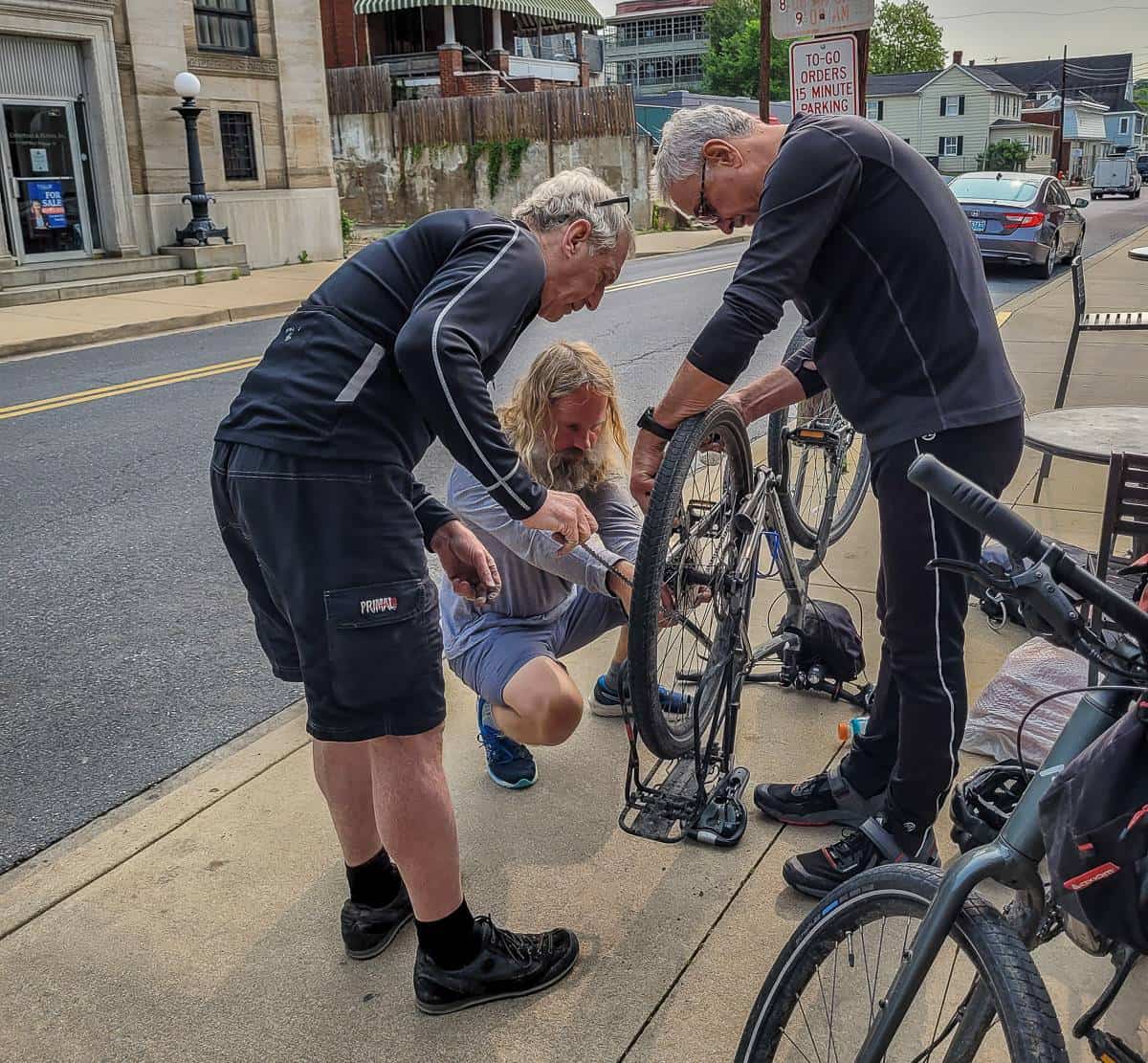 The kindness of strangers helping John get the now repaired chain back on the bike in Brunswick